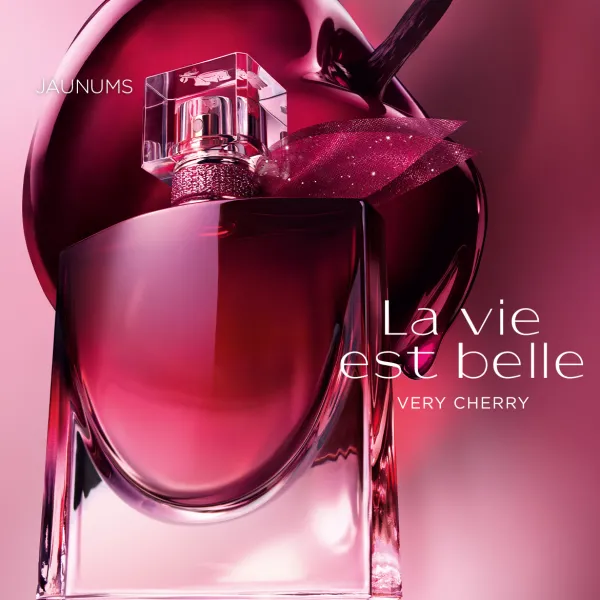 Lancôme La Vie Est Belle Very Cherry smaržu flakons ķiršu toņos uz dekoratīva rozā fona.