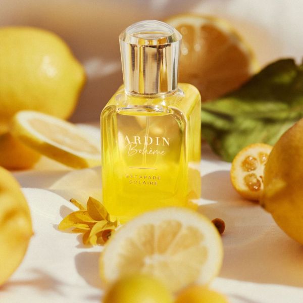 Dzeltens Jardin Bohème Escapade Solaire aromāts, novietots starp svaigiem citroniem saulainā vidē.