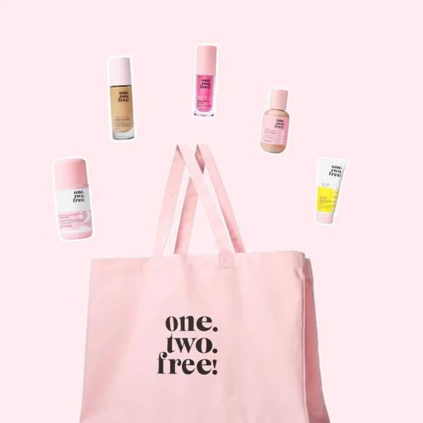 One.two.free! kosmētikas produkti izvietoti ap rozā auduma somu uz gaiši rozā fona.