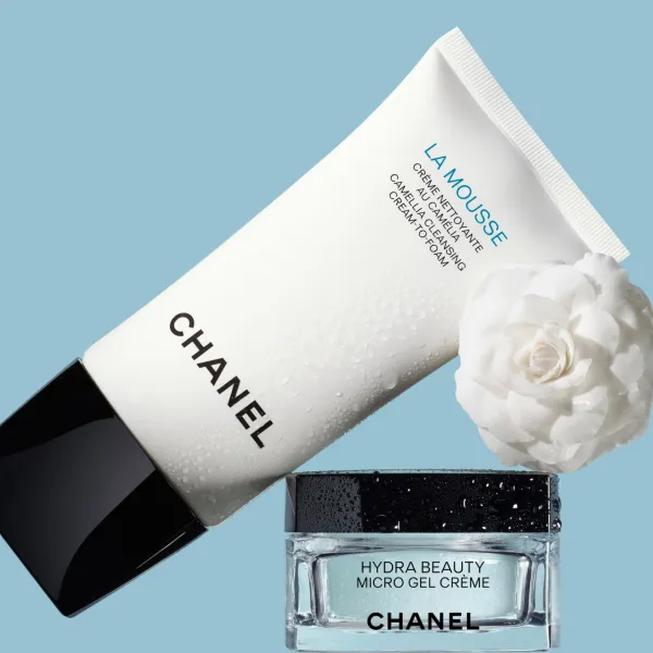 CHANEL La Mousse attīrošais līdzeklis ar Hydra Beauty krēmu un baltām kamēlijām uz zilas fona.