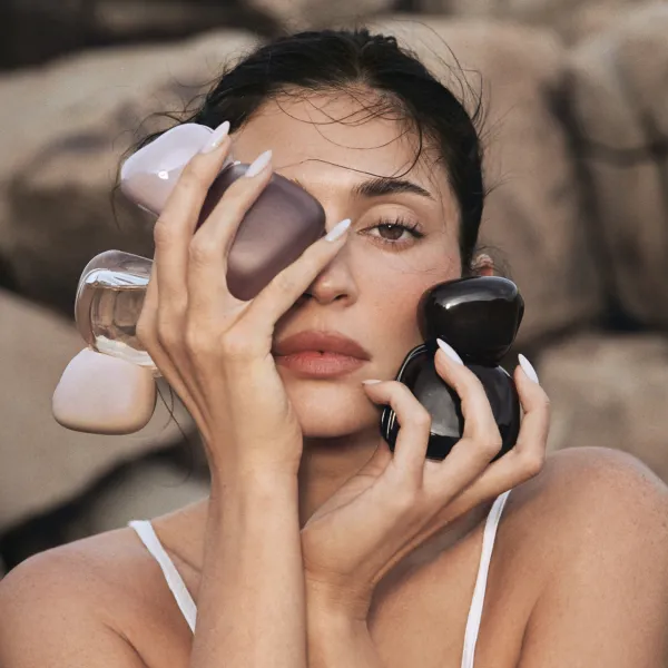 Persona tur rokās vairākas Kylie Fragrances Mood Stones smaržu pudelītes uz akmeņaina fona.