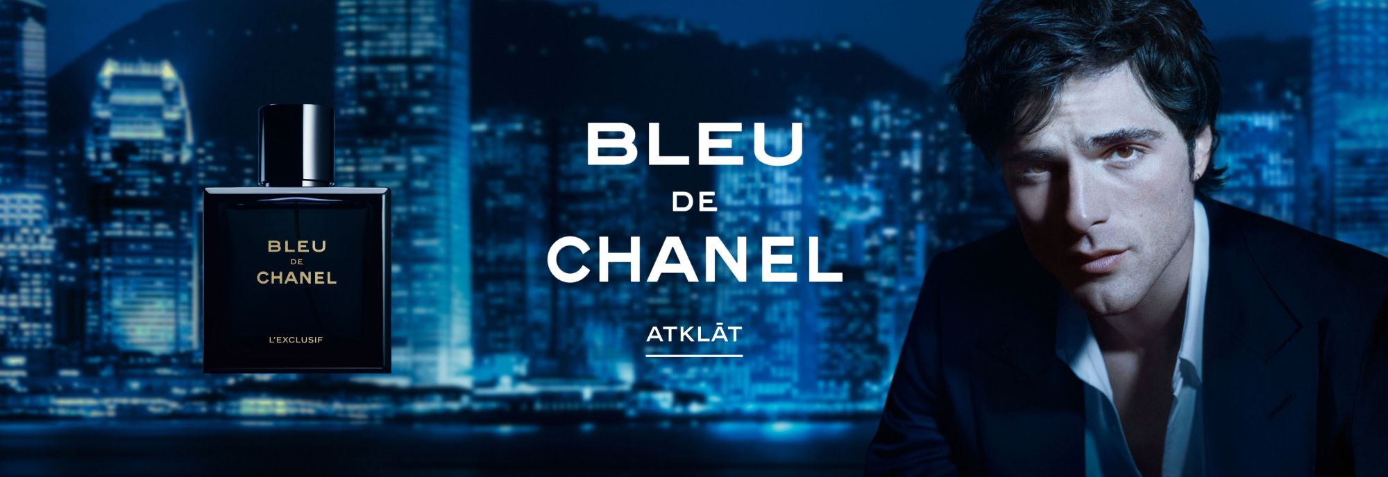 BLEU DE CHANEL smaržu pudelīte uz nakts pilsētas fona un modelis blakus BLEU DE CHANEL smaržu pudelīte uz nakts pilsētas fona un modelis blakus